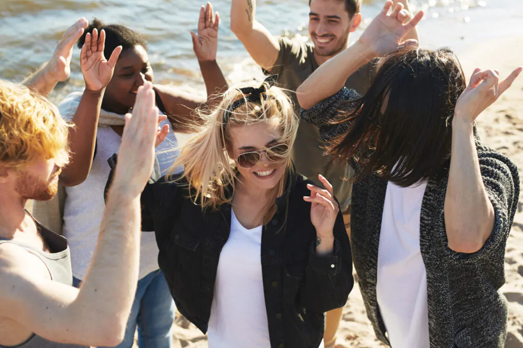 People are dancing merrily with their hands in the air on the beach People dancing on the beach