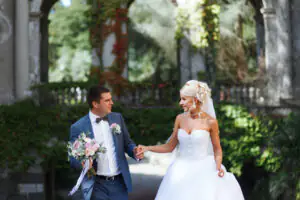 The groom with a wedding bouquet and the bride pose on a beautiful background The bride and groom