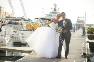 The bride and groom pose against the backdrop of luxury yachts Happy newlyweds