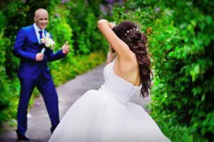 The bride takes pictures of her groom on her mobile phone The bride's back is turned