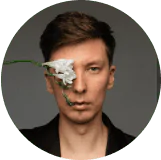 A picture of a guy covering one eye with a flower, in a round frame The guy closes one eye with a flower