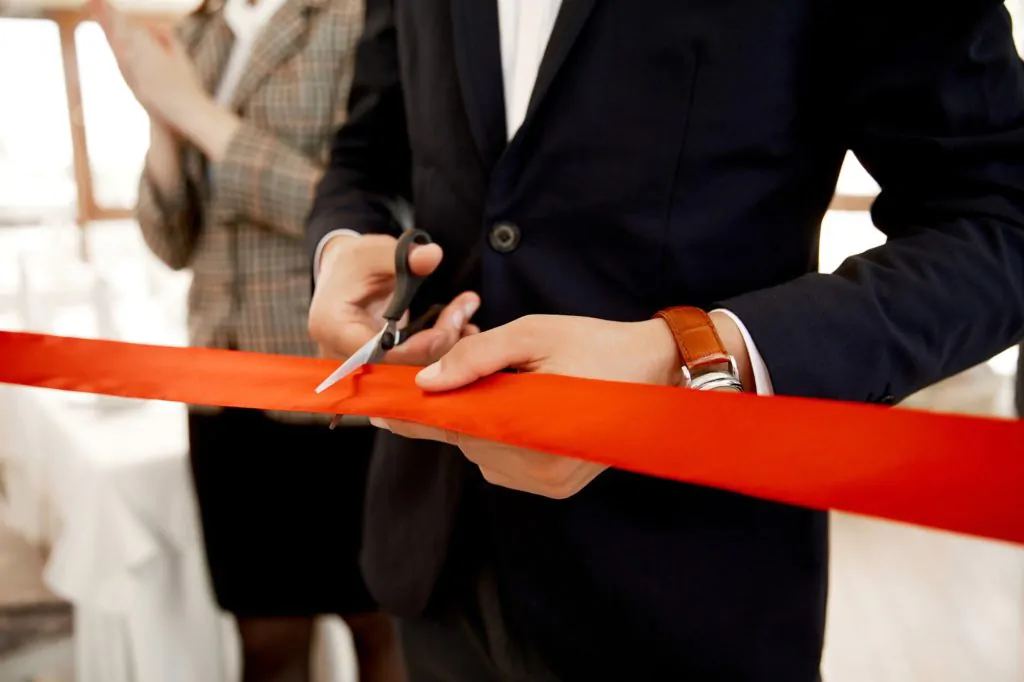 A man in a formal suit cuts a red ribbon Cutting the red ribbon