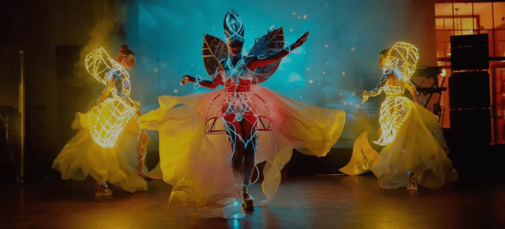 Three girls dancing in magnificent costumes with glowing elements Three dancers in glowing costumes