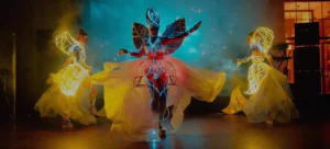 Three dancers in glowing costumes