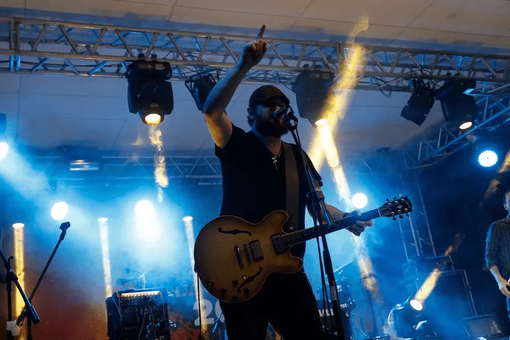 The singer performs on stage with an electric guitar and raises his finger up Performer with an electric guitar