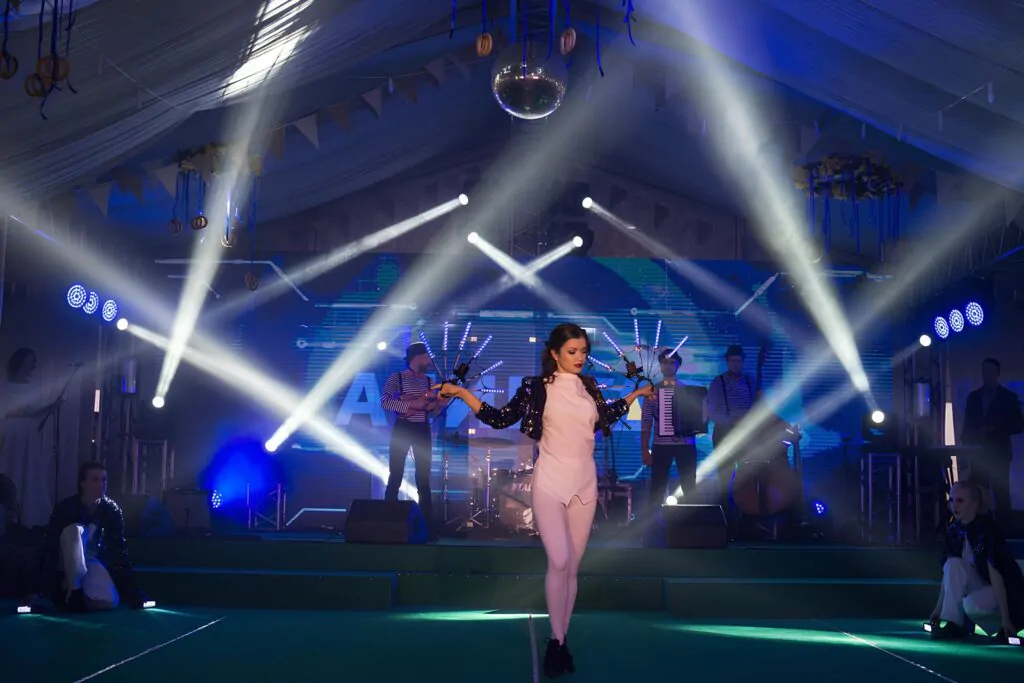 A performer in a sparkling outfit dances on stage with dramatic lighting A performer in a sparkling outfit