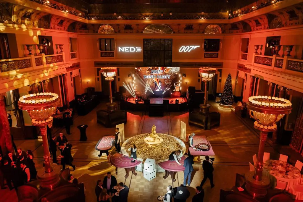 The large hall is decorated for a themed party, with game tables and a stage A room with a stage and playing tables