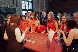 People are standing around the red casino table