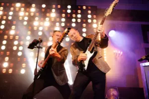 Two musicians perform energetically on stage