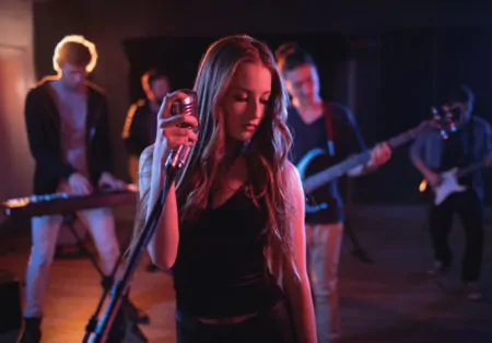 Female singer performing with a musical band in the background Woman in black dress singing with band