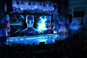 Two presenters on stage with a futuristic background screen Two hosts on stage with futuristic image on screen