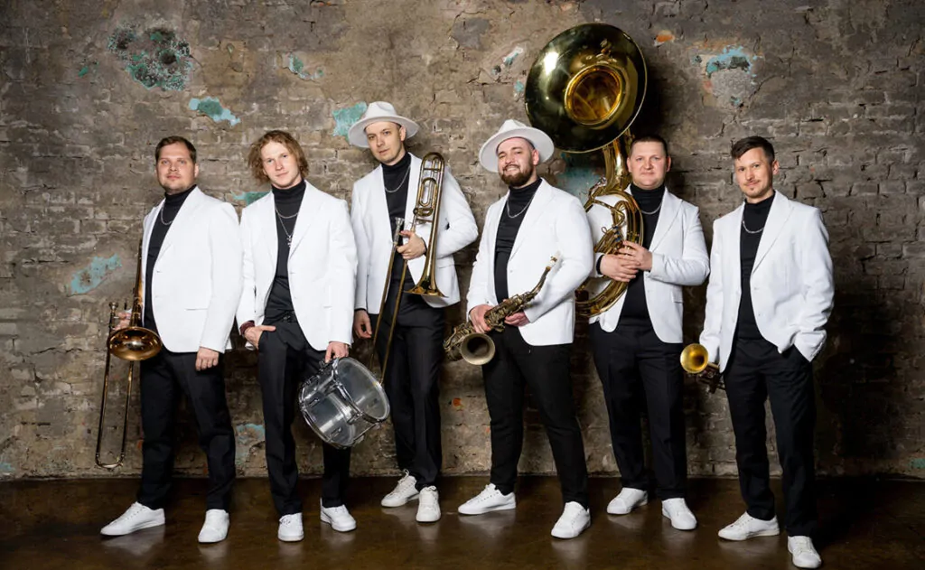 Musicians in white jackets and hats pose with brass and percussion instruments Musicians in white jackets
